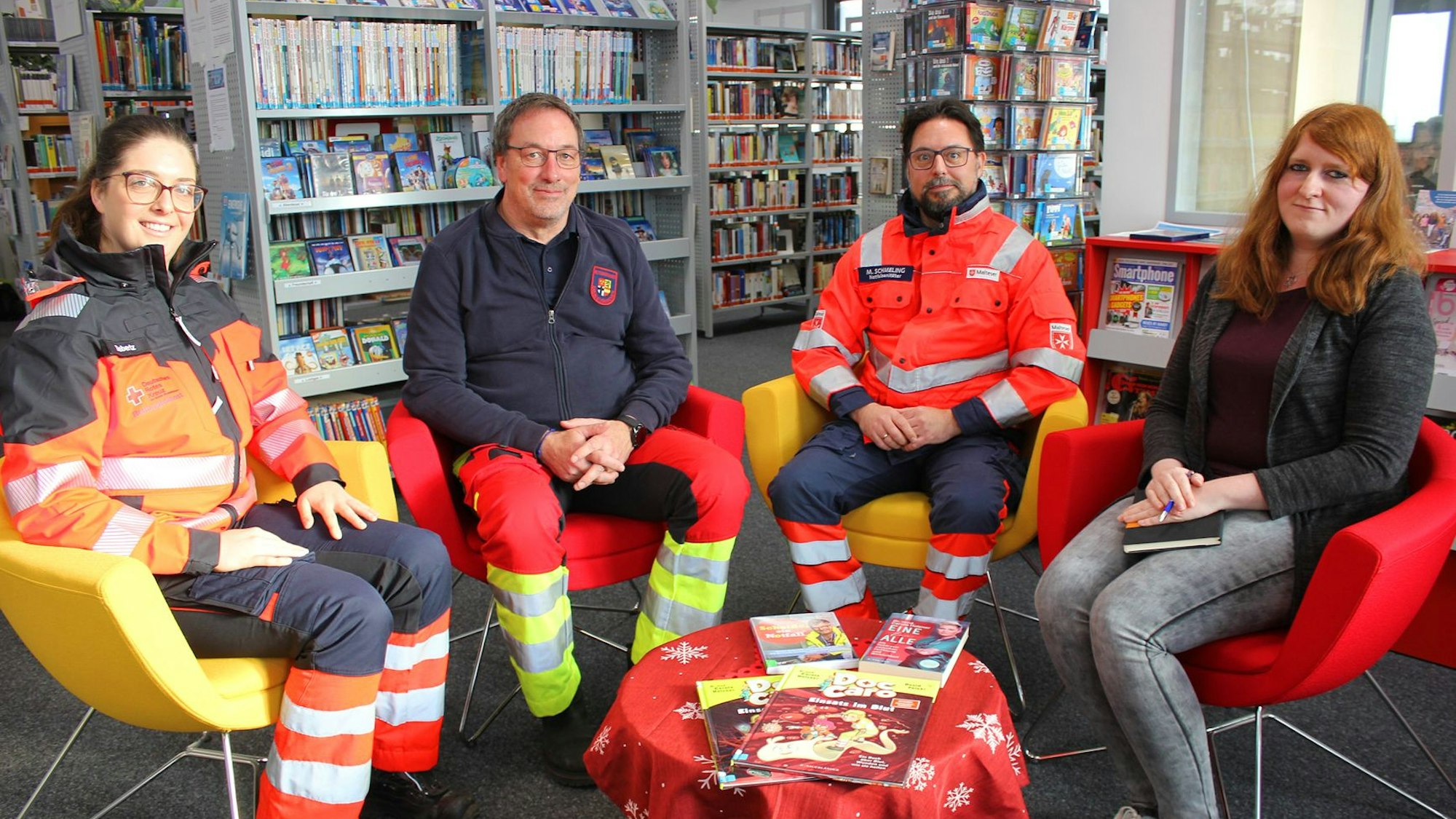 Vanessa Siebertz, Rainer Brück, Michael Schmeling und Michelle Wagner sitzen auf Stühlen in der Gemeinde-Bibliothek.