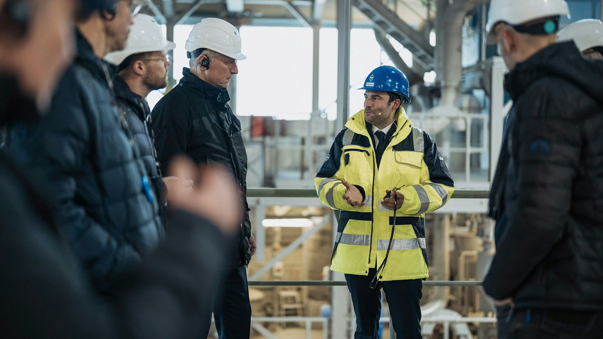 Auf dem Bild sind Männer bei einer Werksbesichtigung zu sehen.
