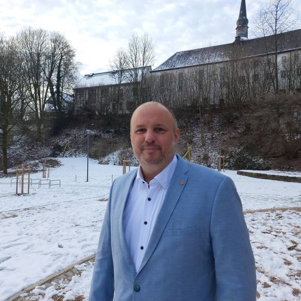 Porträt eines Mannes, der in einem schneebedeckten Park steht.