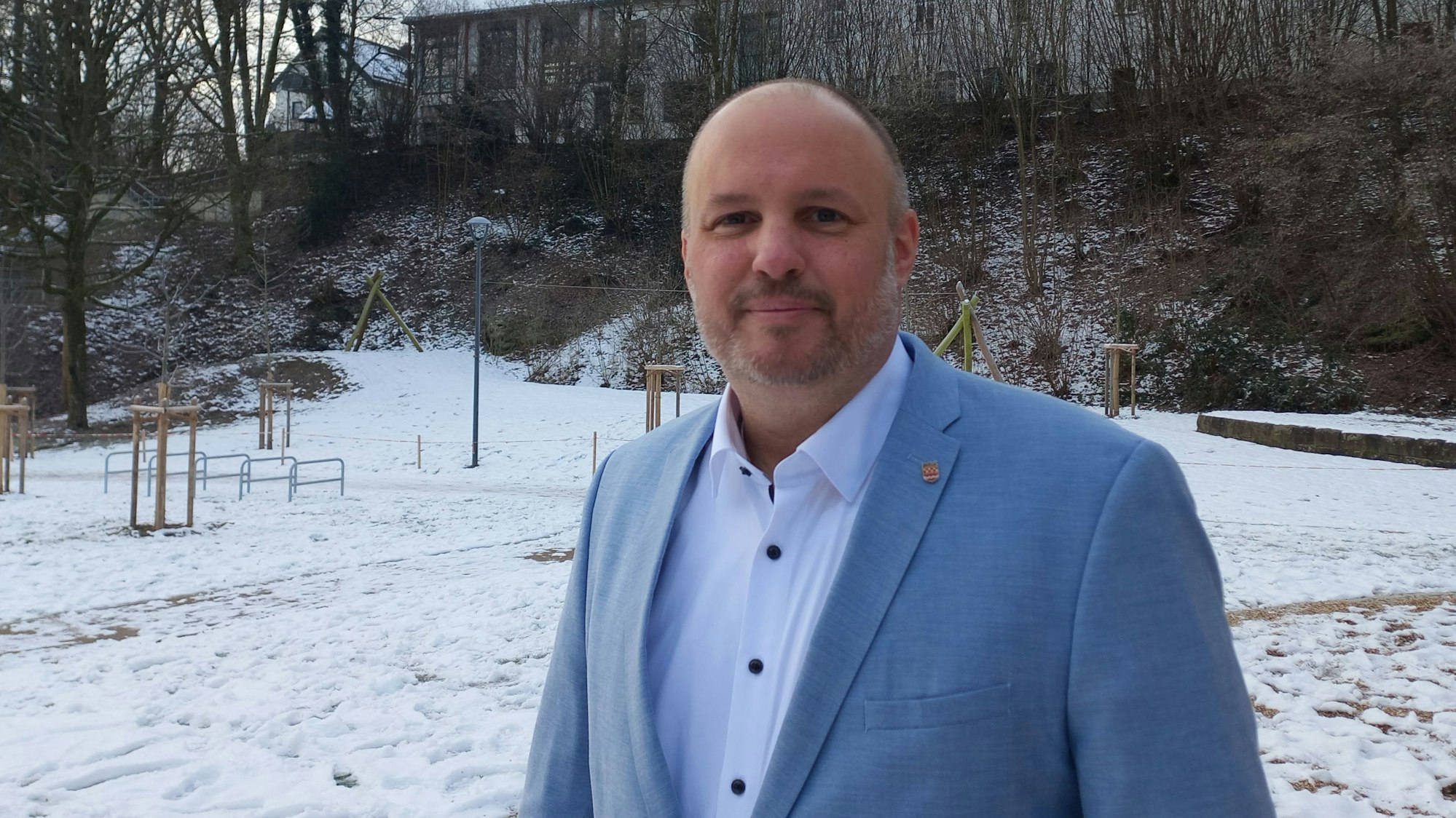 Porträt eines Mannes, der in einem schneebedeckten Park steht.