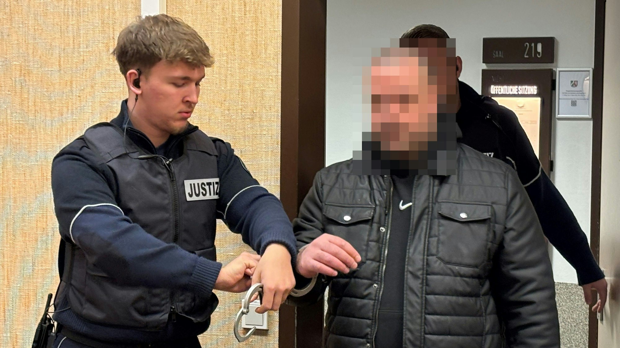 Ein Angeklagter wird in Handschellen in den Verhandlungssaal beim Kölner Landgericht geführt.