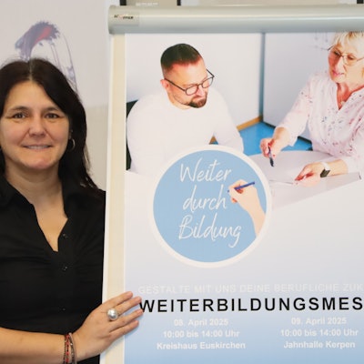 Eine Frau steht neben einem Plakat.