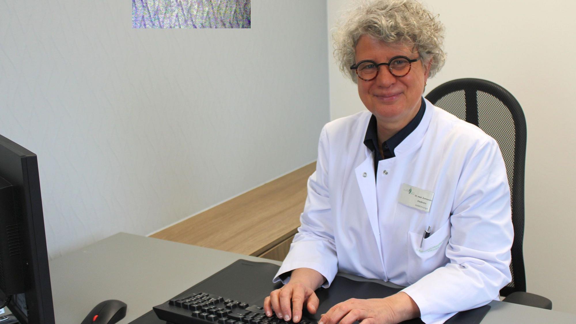 Auf dem Bild ist eine Ärztin zu sehen, die an einem Computer sitzt.