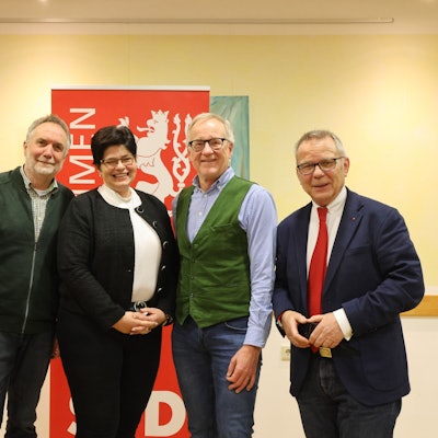 Vier Männer und eine Frau posieren vor einem SPD-Banner.