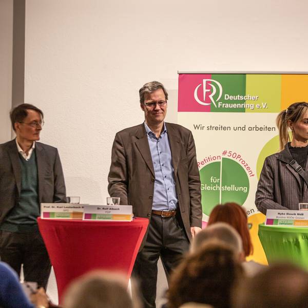 Zwei Männer und eine Frau stehen auf einem Podium.