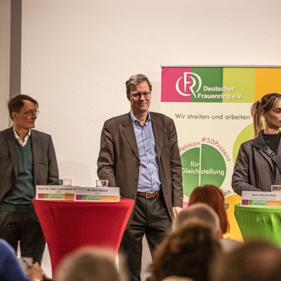 Zwei Männer und eine Frau stehen auf einem Podium.