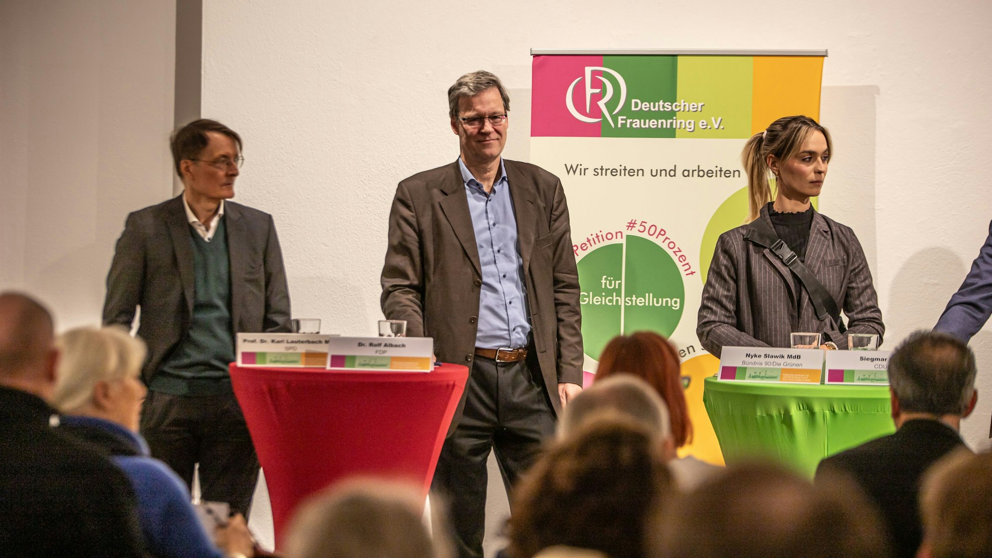 Zwei Männer und eine Frau stehen auf einem Podium.