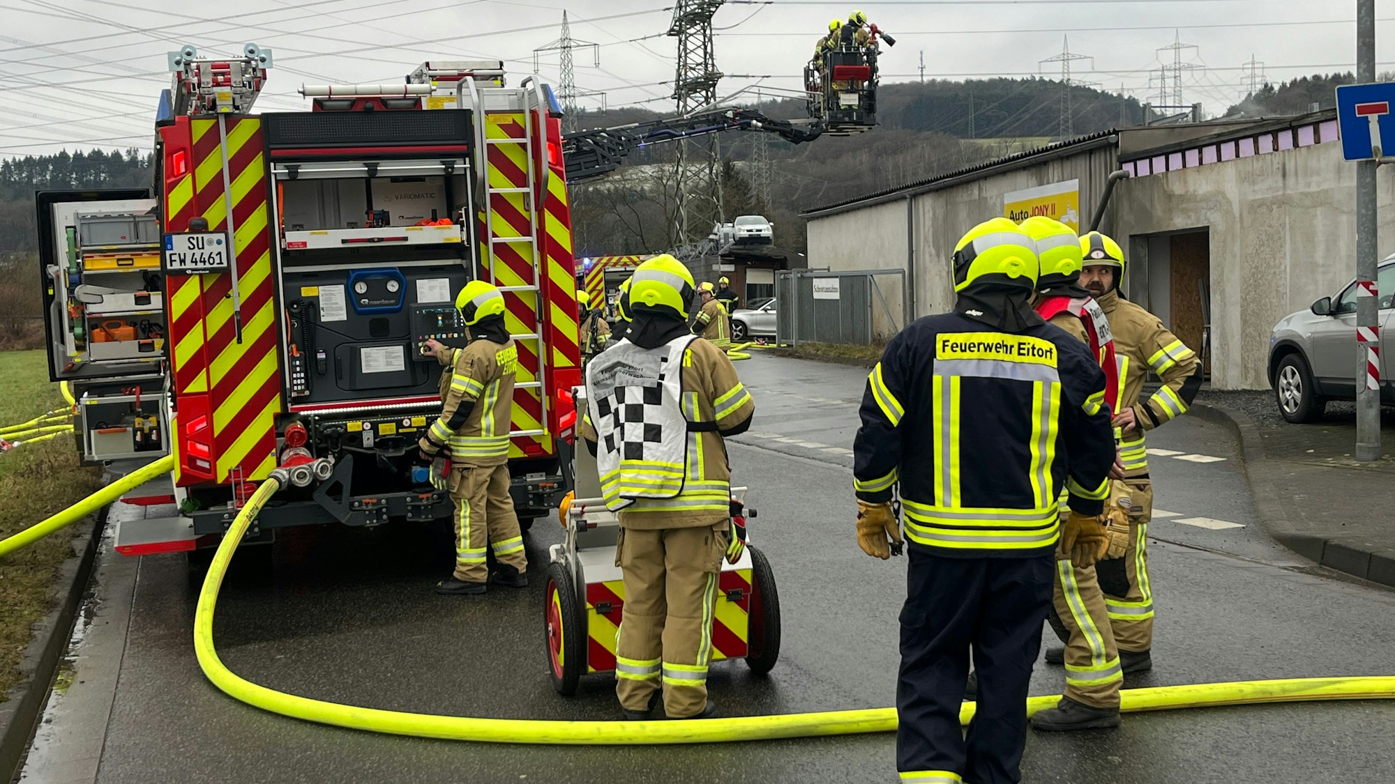 Feuerwehrleute stehen um ein Feuerwehrauto, im Korb einer Drehleiter stehen Einsatzkräfte.