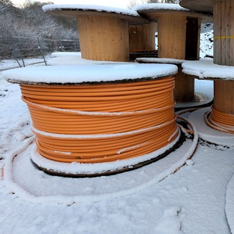 Kabeltrommeln mit Glasfaserleitungen im Schnee.