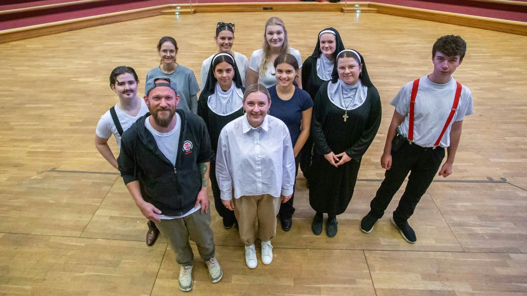 Eine Gruppe von elf jungen Frauen und Männern stehen zusammen, zwei Mädchen tragen Nonnen-Kostüme.