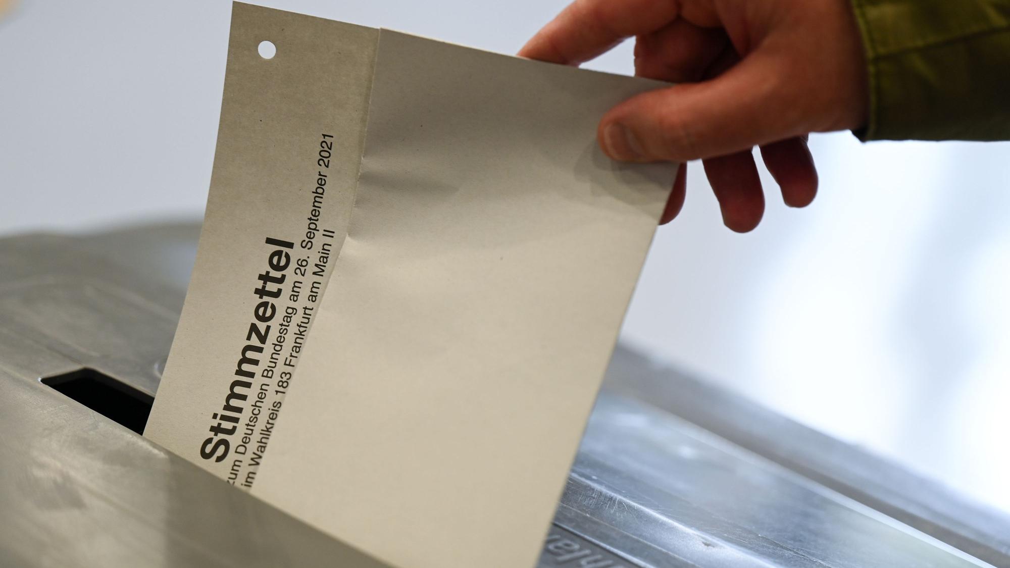 Ein Mann steckt im Wahllokal in der Freiherr-von-Stein-Schule im Stadtteil Sachsenhausen seinen Stimmzettel für die Bundestagswahl 2021 in eine Wahlurne.