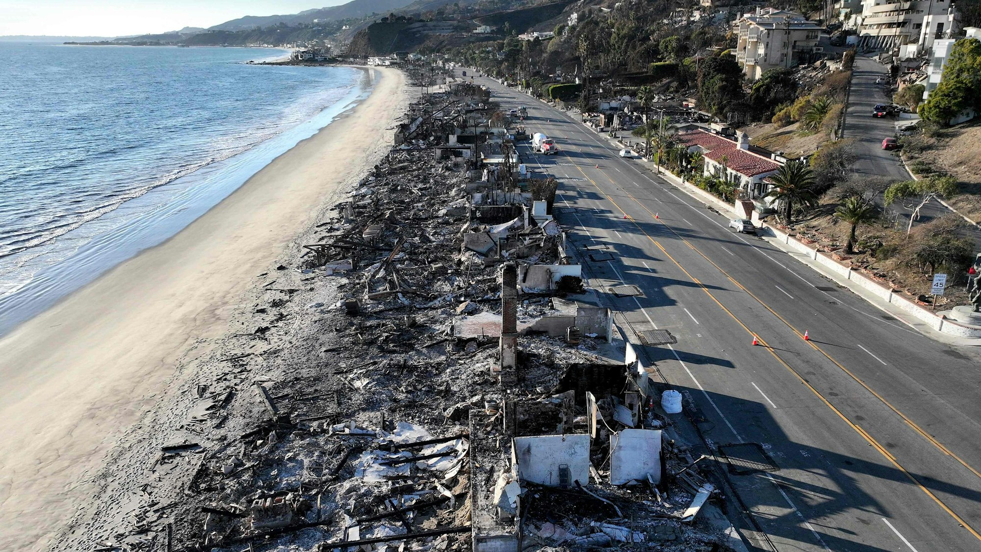 Eine heruntergebrannte Häuserreihe am Strand, aus der Luft gesehen.