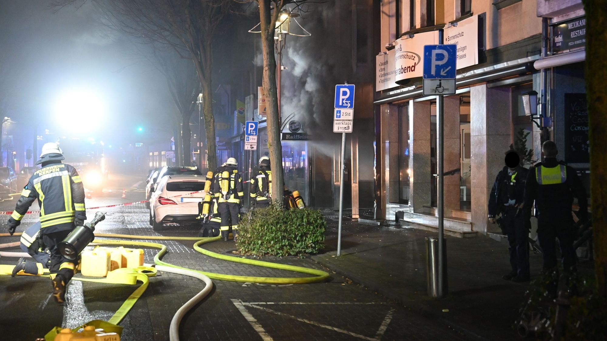 Das Bild zeigt Feuerwehrleute und Polizisten im Bereich der Bankfiliale.