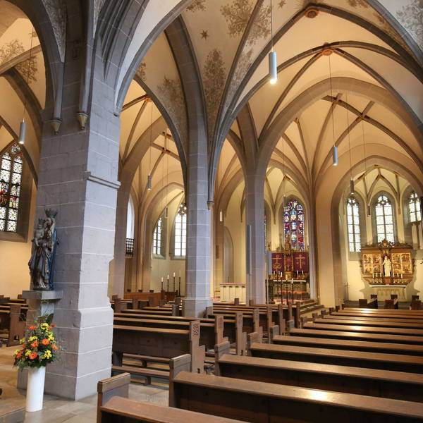 Blick in das Innere einer Kirche, im Vordergrund die Kirchenbänke, im Hintergrund zwei Altäre.