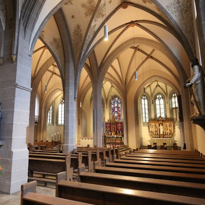 Blick in das Innere einer Kirche, im Vordergrund die Kirchenbänke, im Hintergrund zwei Altäre.