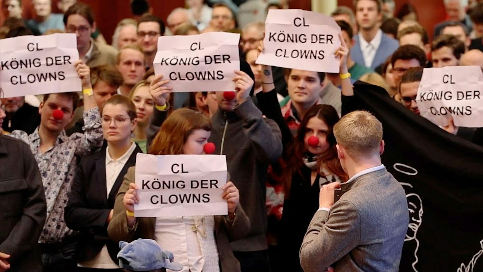 Während der Rede des FDP-Vorsitzenden Christian Lindner halten Protestierende Plakate mit der Aufschrift ‚CL König der Clowns‘ bei einer Wahlkampfveranstaltung im Kolpinghaus in Regensburg hoch. Die jungen Demonstranten tragen dabei zum Teil rote Clownsnasen.