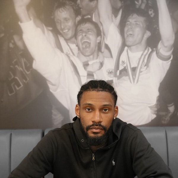 Dominic Duncan sitzt an einem Tisch und unterschreibt seinen Vertrag.