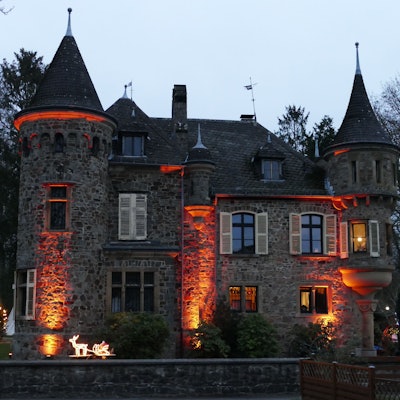 Eine angestrahlte Burg mit zwei Türmen.