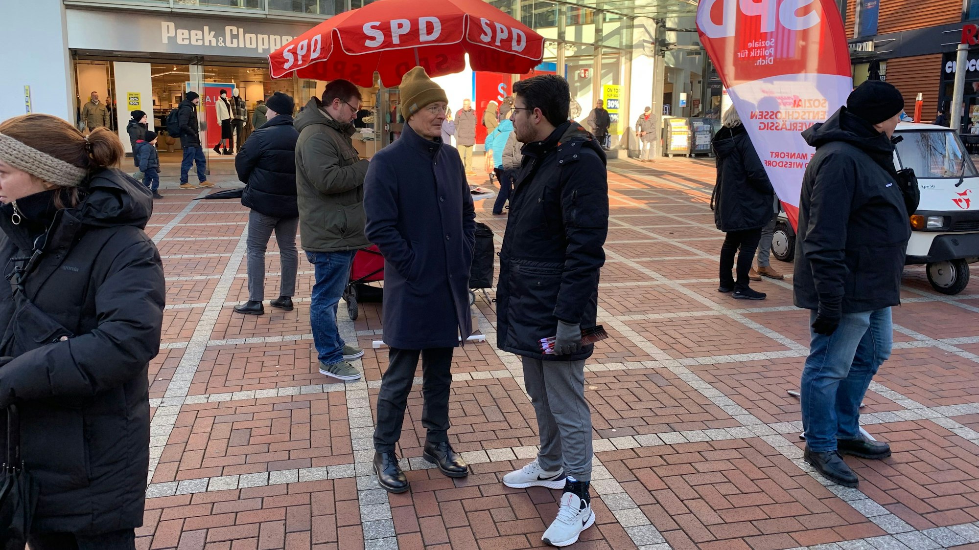 Zwei Männer unterhalten sich in einer Fußgängerzone.