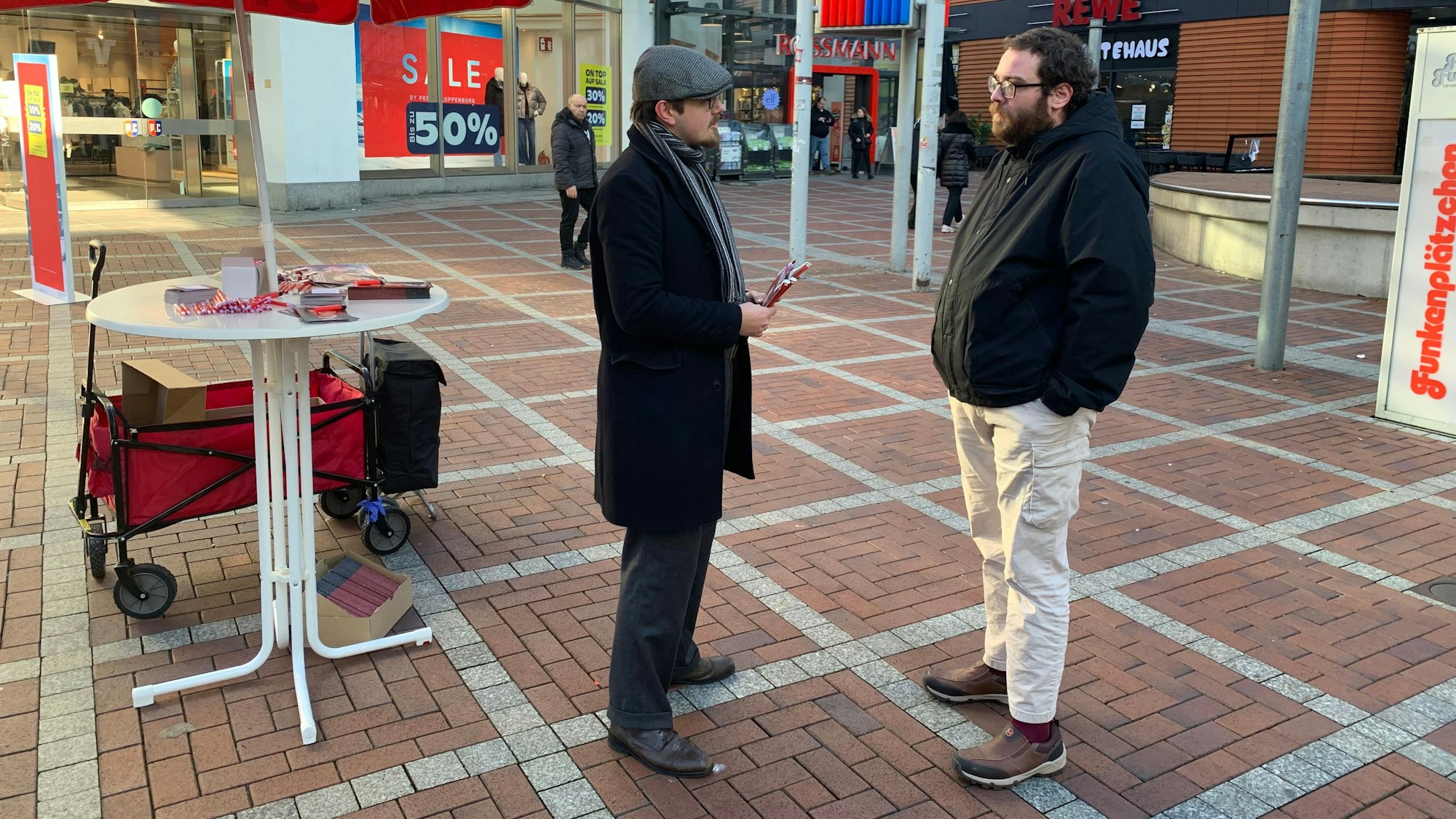 Zwei Männer unterhalten sich in einer Fußgängerzone.