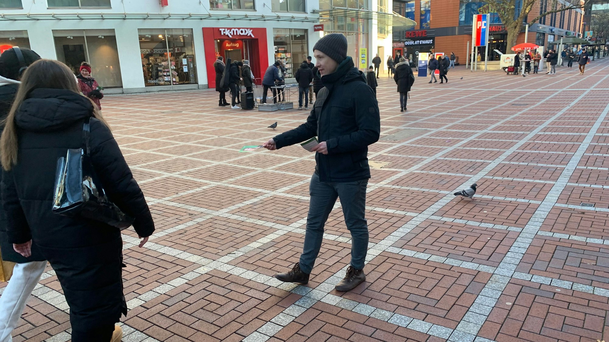 Ein Mann verteilt Flyer in einer Fußgängerzone.