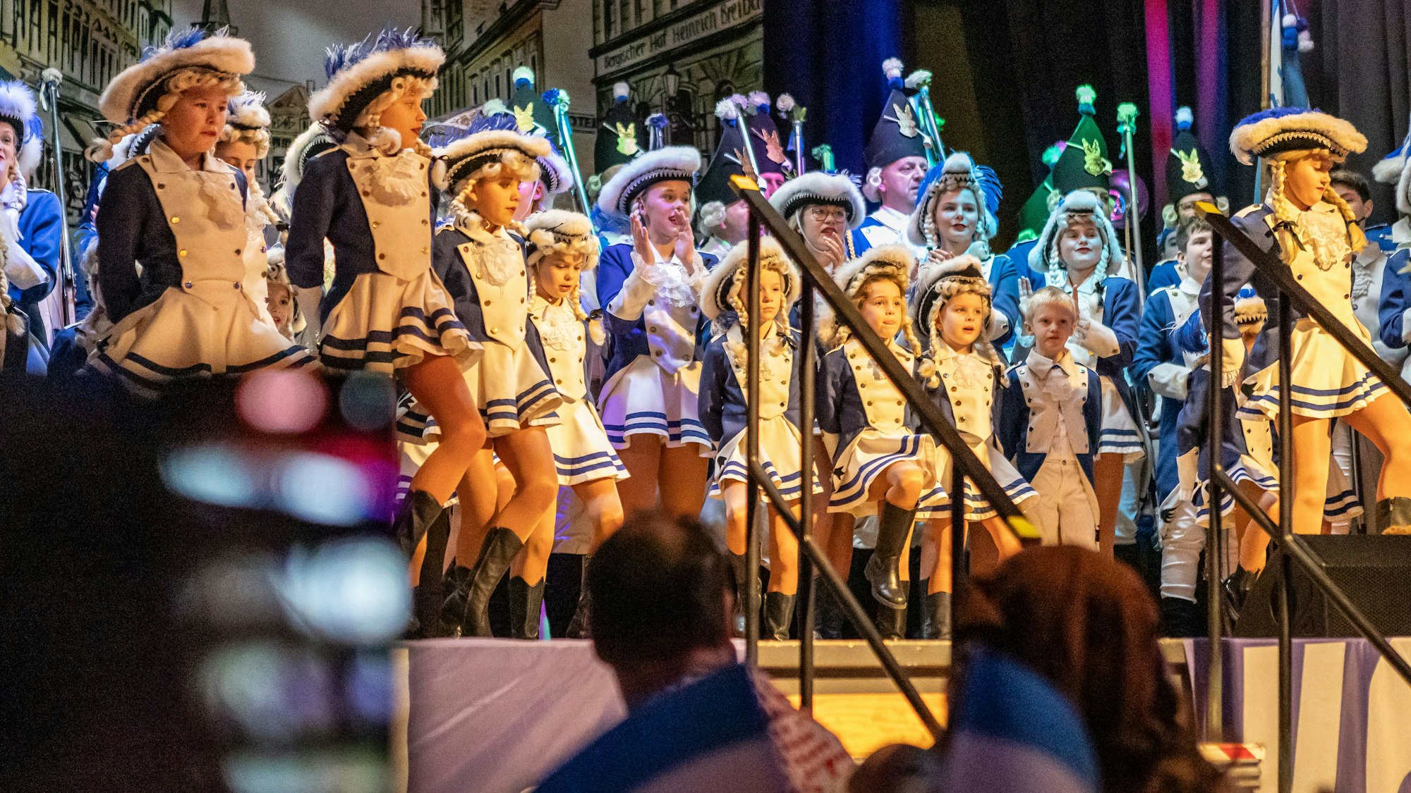 Junge Karnevalistinnen singen und tanzen auf einer Bühne.