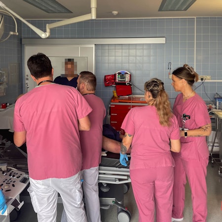 Mitarbeiter der Zentralen Notaufnahme des Marien-Hospitals in Euskirchen in rosafarbener Arbeitskleidung kümmern sich um einen Patienten.