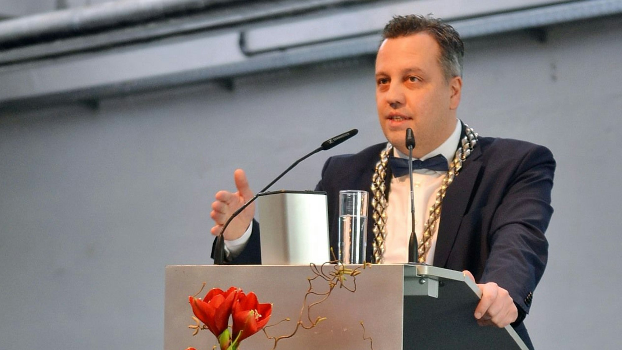 Sacha Reichelt steht am Rednerpult. Er trägt einen dunklen Anzug mit Fliege und seine Bürgermeisterkette.
