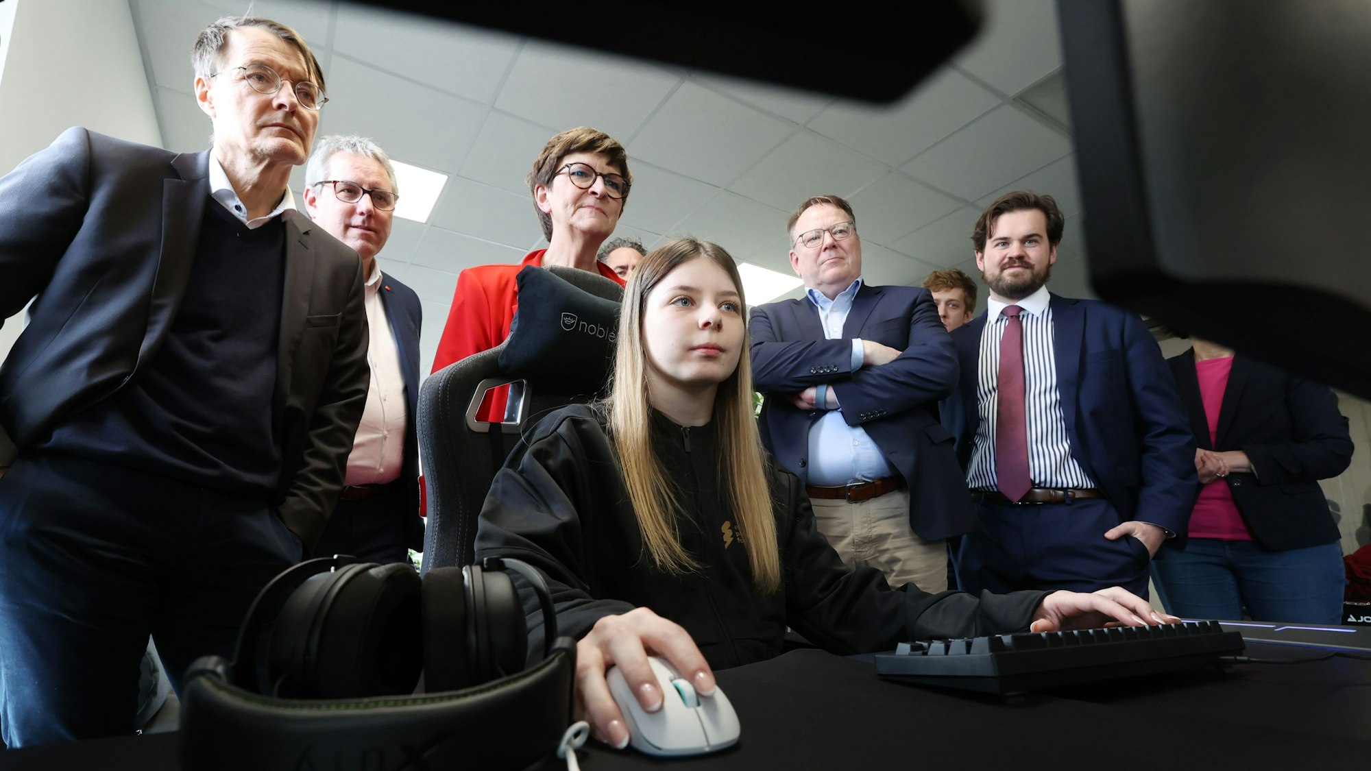 Gesundheitsminister Karl Lauterbach (links) und weitere SPD-Politiker schauen in Köln der E-Sportlerin Sahrii über die Schulter.