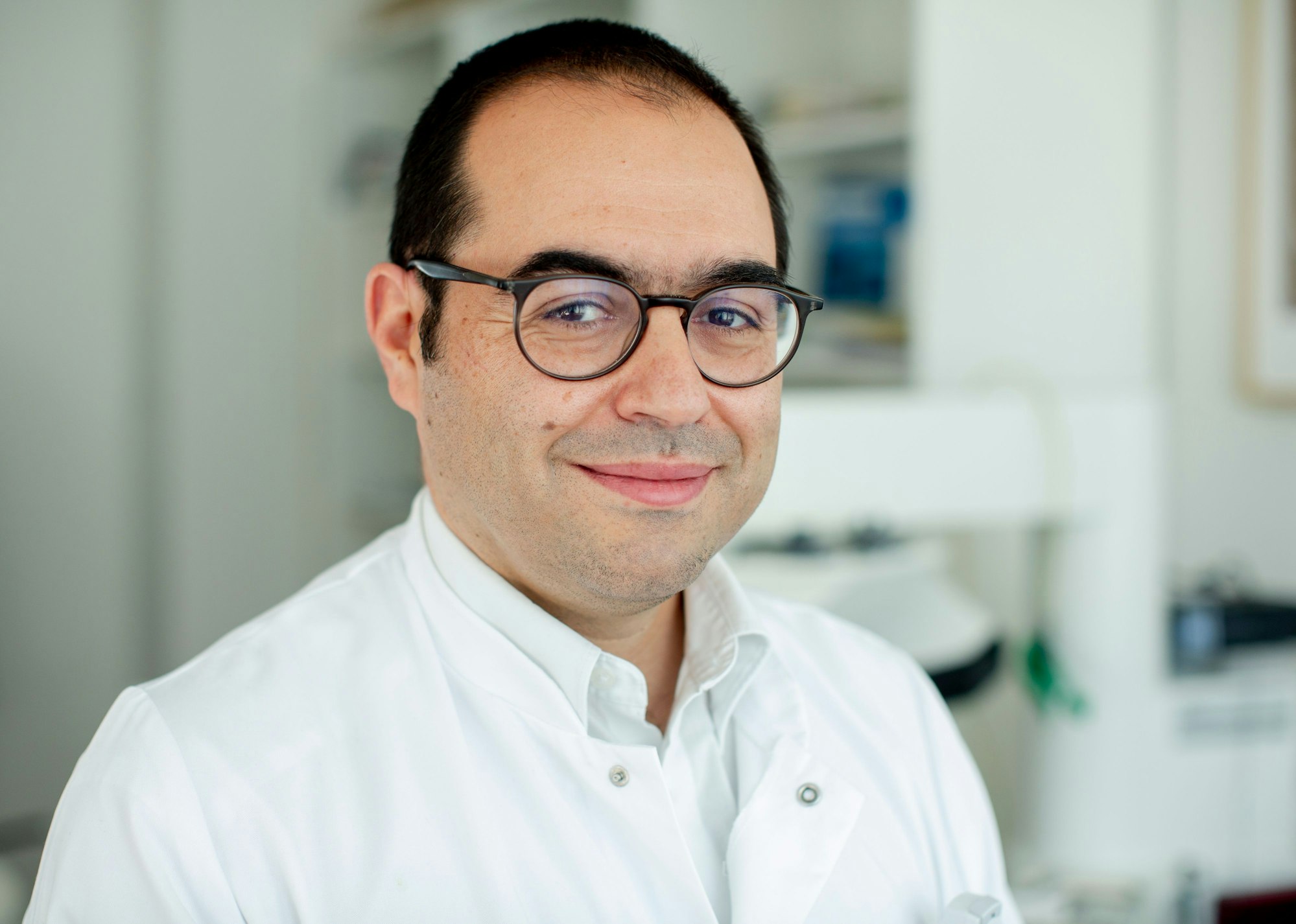 Dr. Özgür Onur ist mit Arztkittel und Brille im Porträt zu sehen.