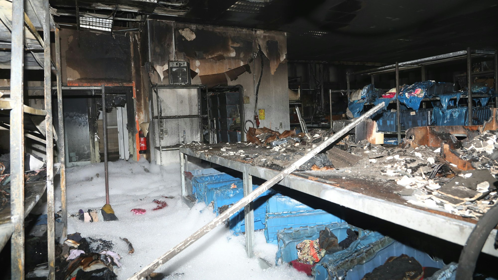 Blick ins Innere der Lagerhalle: Der Löschschaum steht hüfthoch, sämtliche Kleiderspenden sind zerstört.