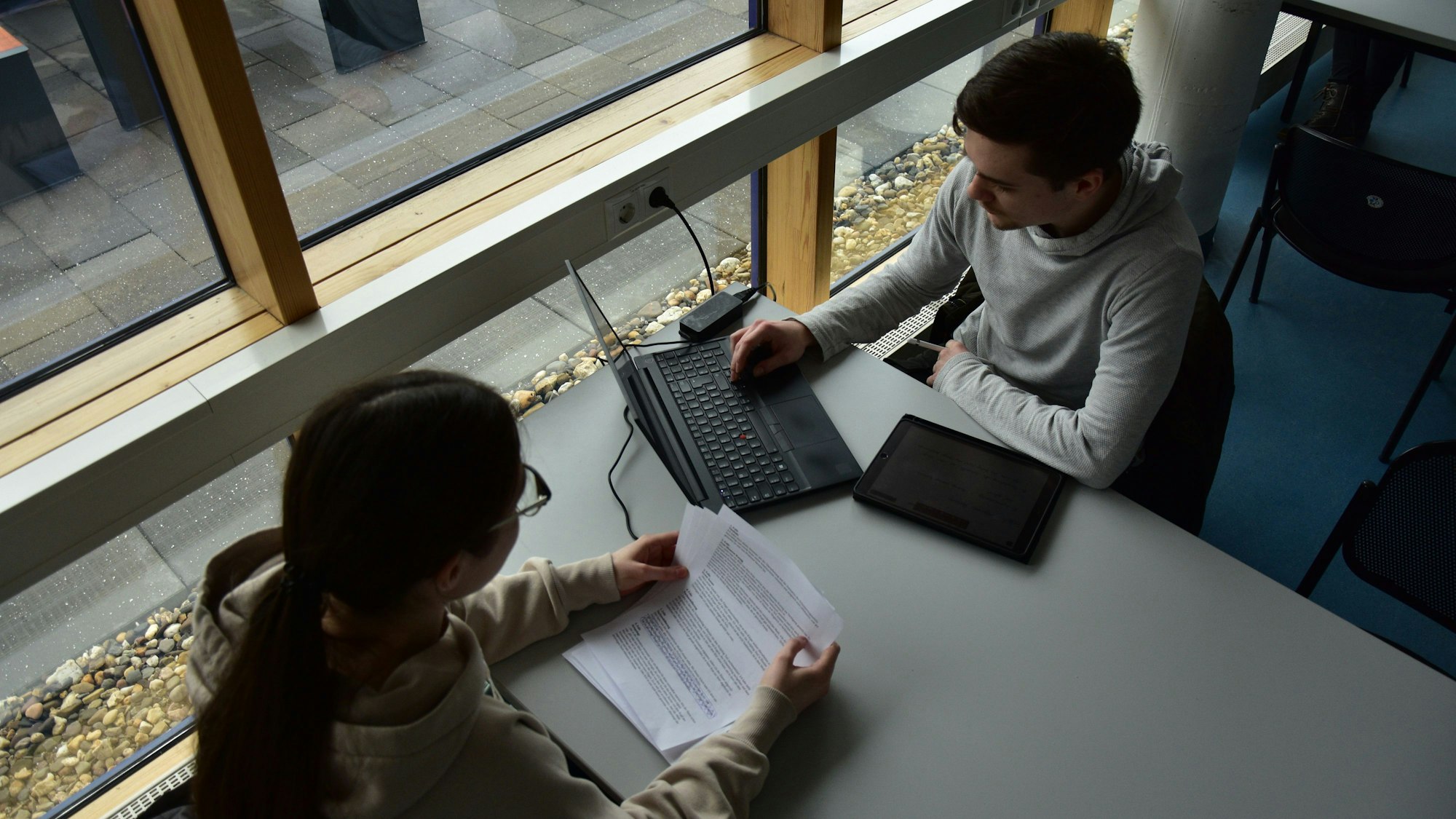 Junge Leute sitzen an einem Tisch und arbeiten am Laptop.