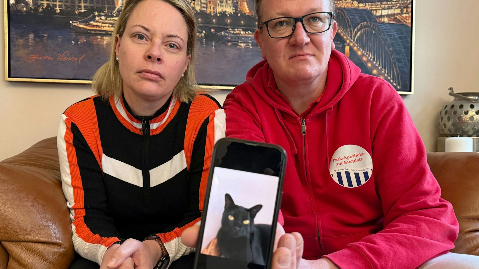 Catharina Majert und ihr Mann Gunnar zeigen auf einem Smartphone ein Foto ihrer Bombay-Katze „Aramis“.