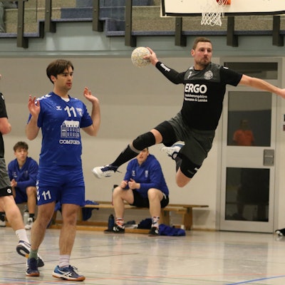 Kalls Handballer Christopher Schmitz steht beim Sprungwurf in der Luft. Sein Gegenspieler hebt die Hände und will mit der Sache nichts zu tun haben.