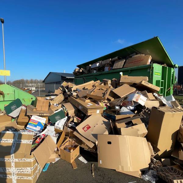 Auf einem Platz in Euskirchen stehen grüne Container. Sie sind mit Altpapier befüllt. Auch davor türmt sich Altpapier, das nicht mehr in die Container passt.