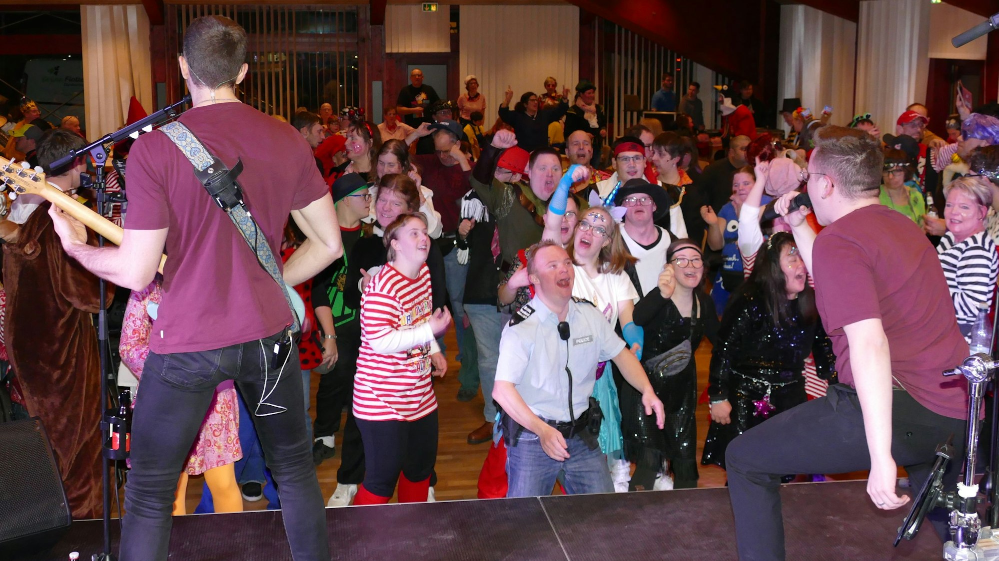 Eine Band spielt auf der Bühne, davor tanzen kostümierte Menschen.