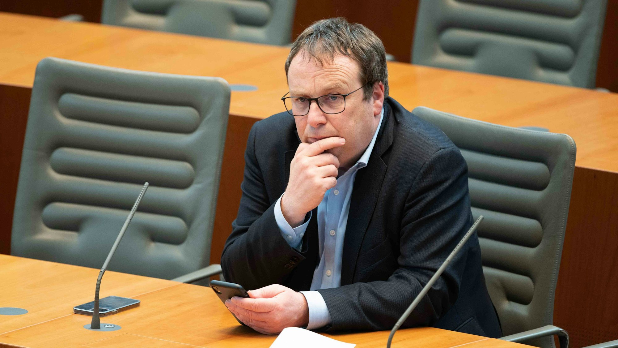 Oliver KRISCHER, Buendnis 90/die Gruenen, Minister fuer Umwelt, Naturschutz und Verkehr des Landes Nordrhein-Westfalen, ist mit Handy in der Hand im Landtag zu sehen.