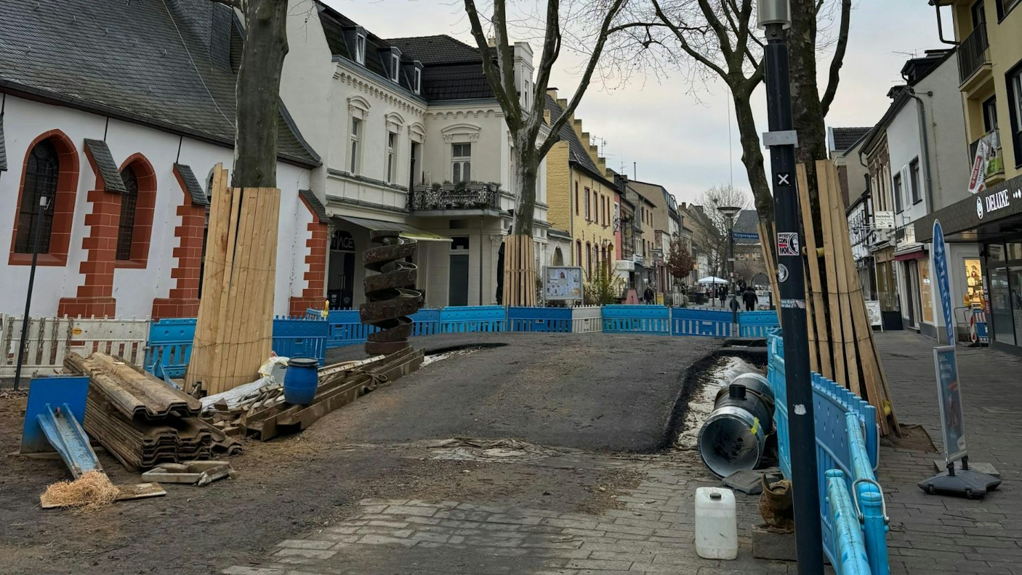 Das Foto zeigt eine Asphaltbrücke zwischen Bäumen in der Bergheimer Innenstadt.