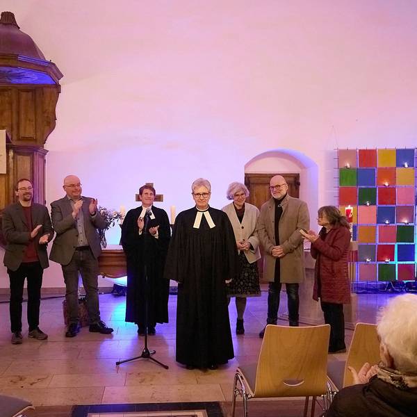 Die Pfarrerin ist vorgetreten, während ihre Amtskollegen und Vertreter der beiden evangelischen Kirchengemeinden im Hintergrund applaudieren.