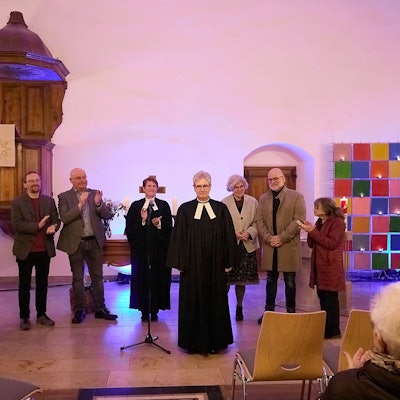 Die Pfarrerin ist vorgetreten, während ihre Amtskollegen und Vertreter der beiden evangelischen Kirchengemeinden im Hintergrund applaudieren.