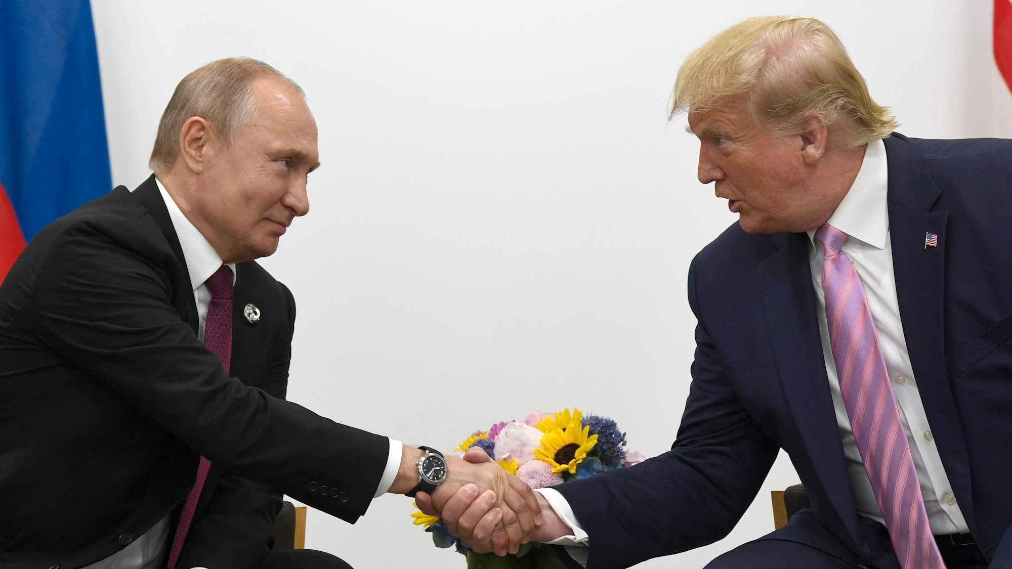28.06.2019, Japan, Osaka: Wladimir Putin (l), Präsident von Russland, und Donald Trump, Präsident der USA, geben sich während des G20-Gipfels die Hand.