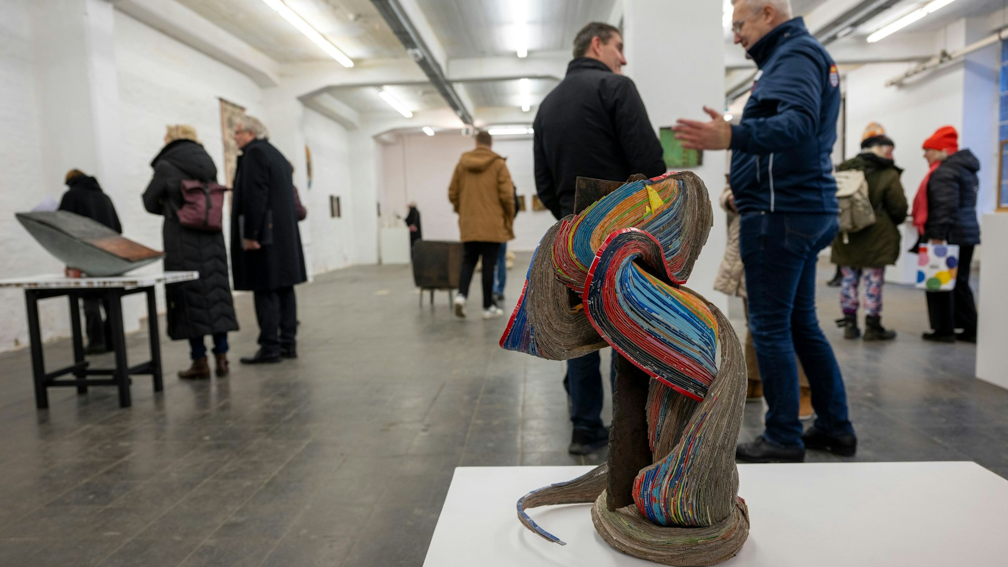 Das Foto zeigt ein Kunstwerk der Ausstellung. Im Hintergrund sind Besucher zu sehen.