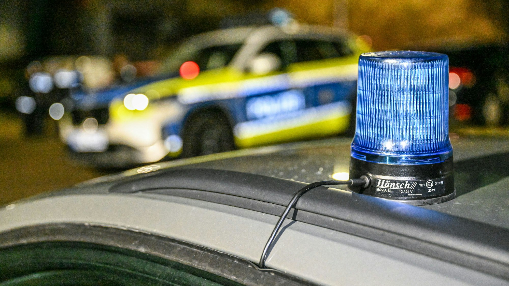 Polizeiautos sperren eine Straße in der Nacht.