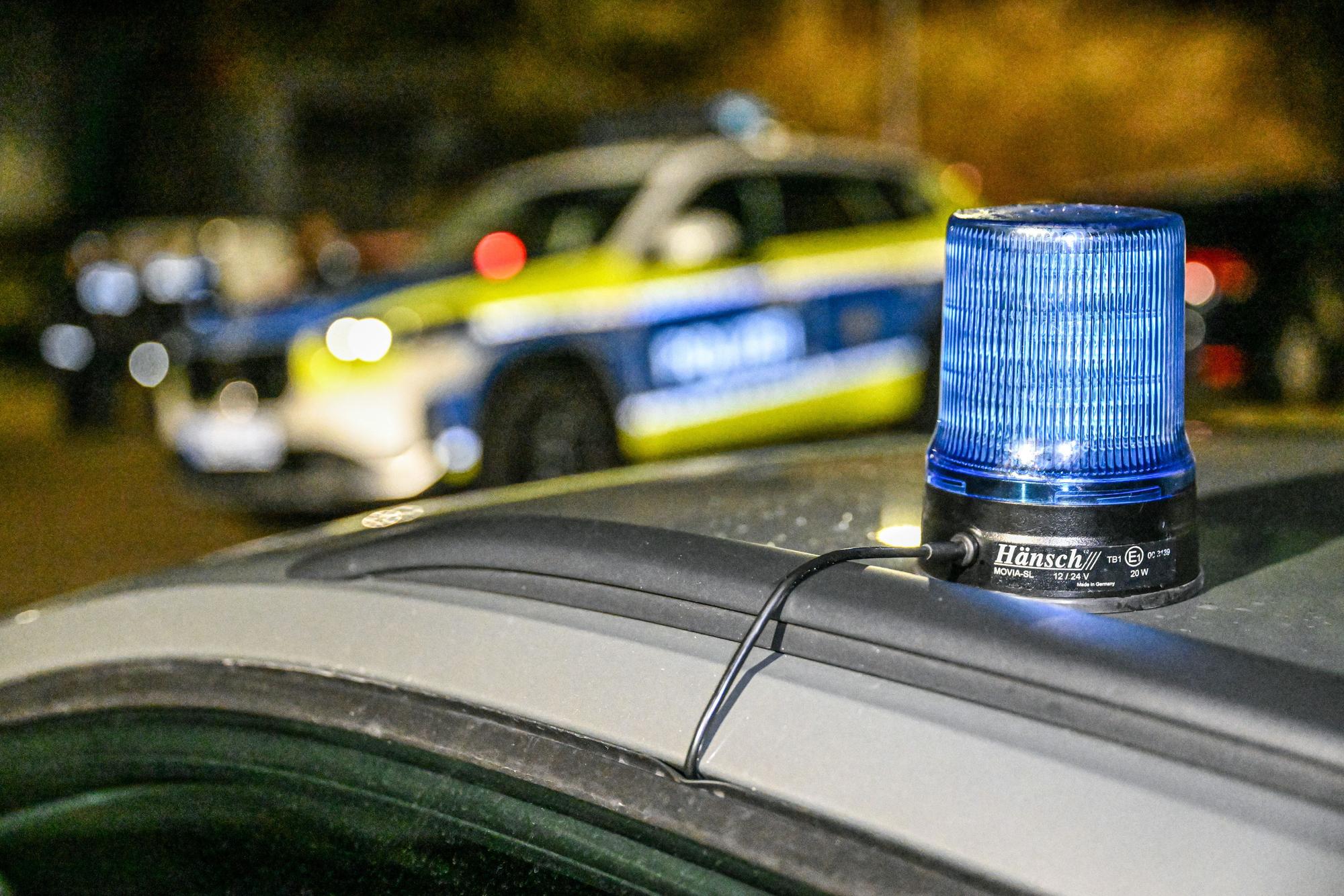 Ein Polizeiwagen mit Blaulicht sperrt eine Straße in der Abenddämmerung.