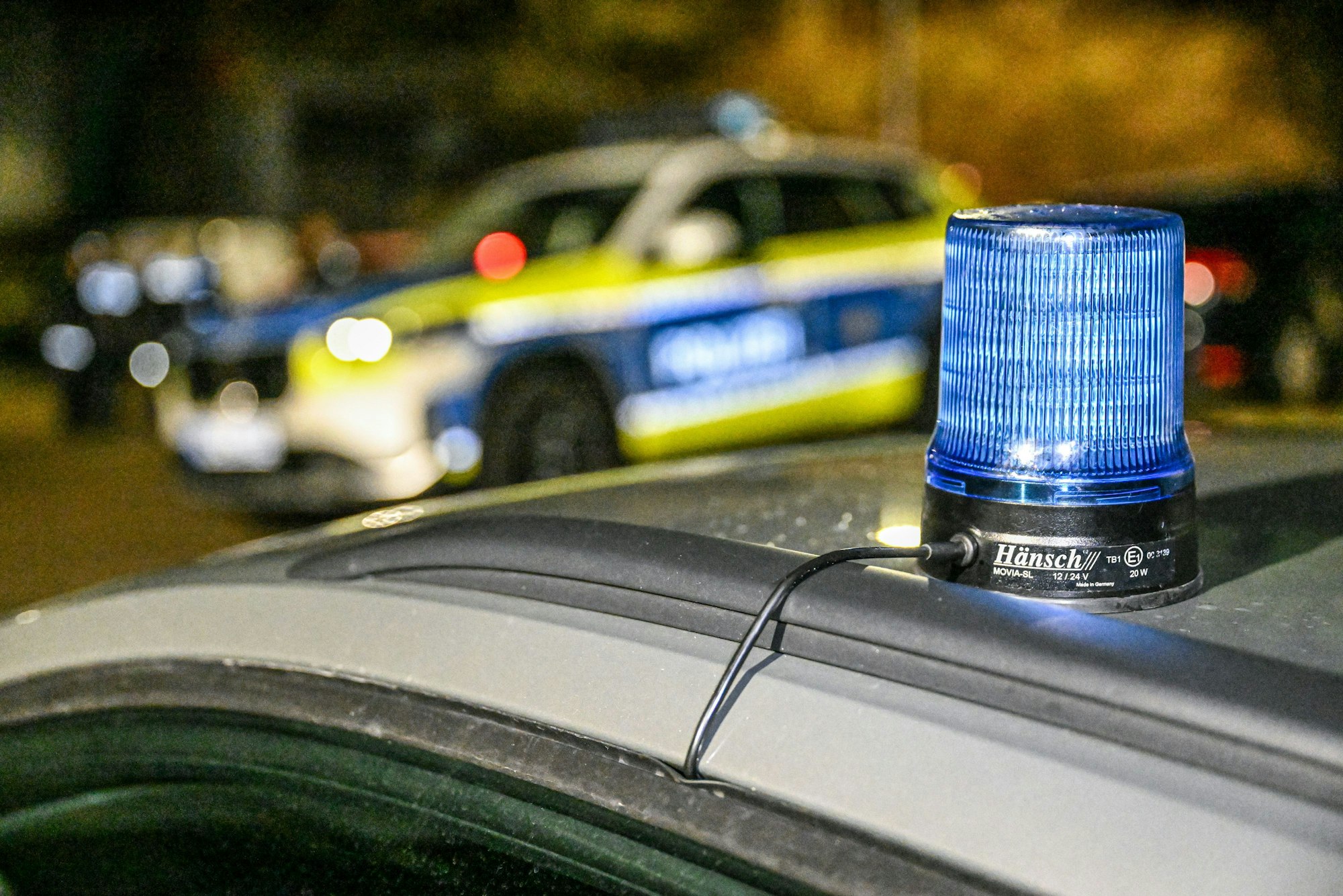 Ein Polizeiwagen mit Blaulicht sperrt eine Straße in der Abenddämmerung.