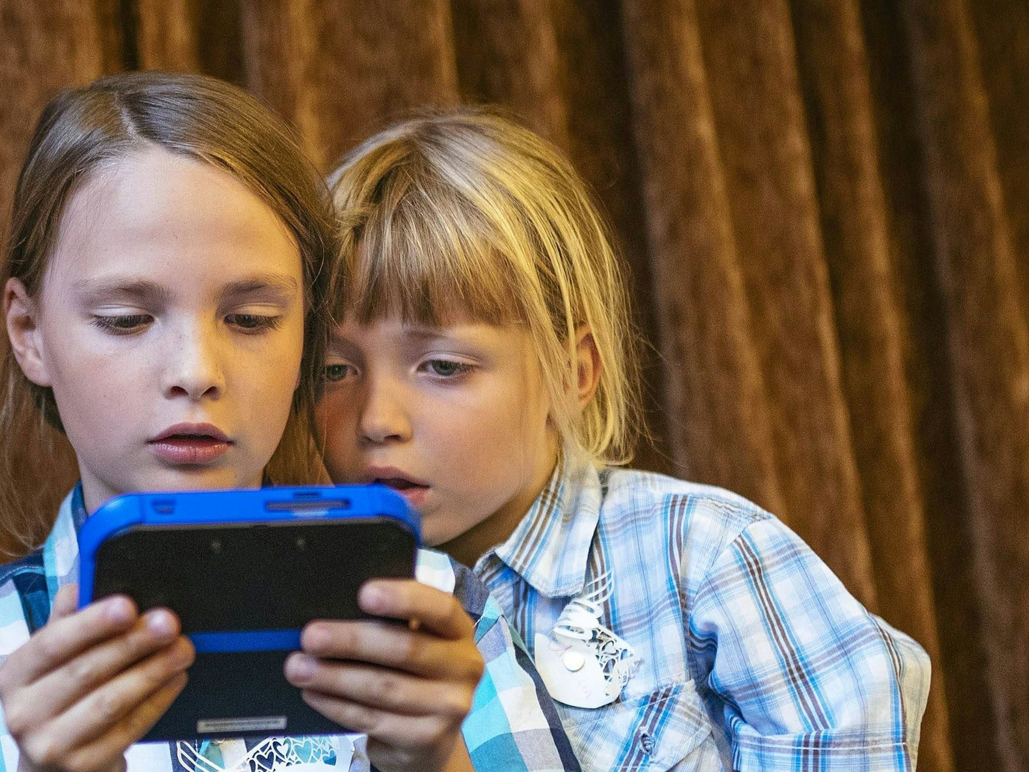 Zwei Kinder schauen mit erschrecktem Gesicht auf ein Display.