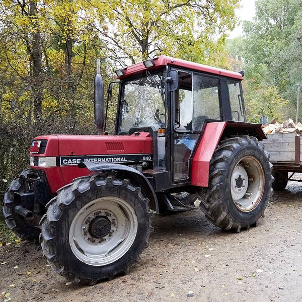 Ein älterer, roter Traktor steht im November 2023 mit einer Fuhre Holz auf einem Waldweg.
