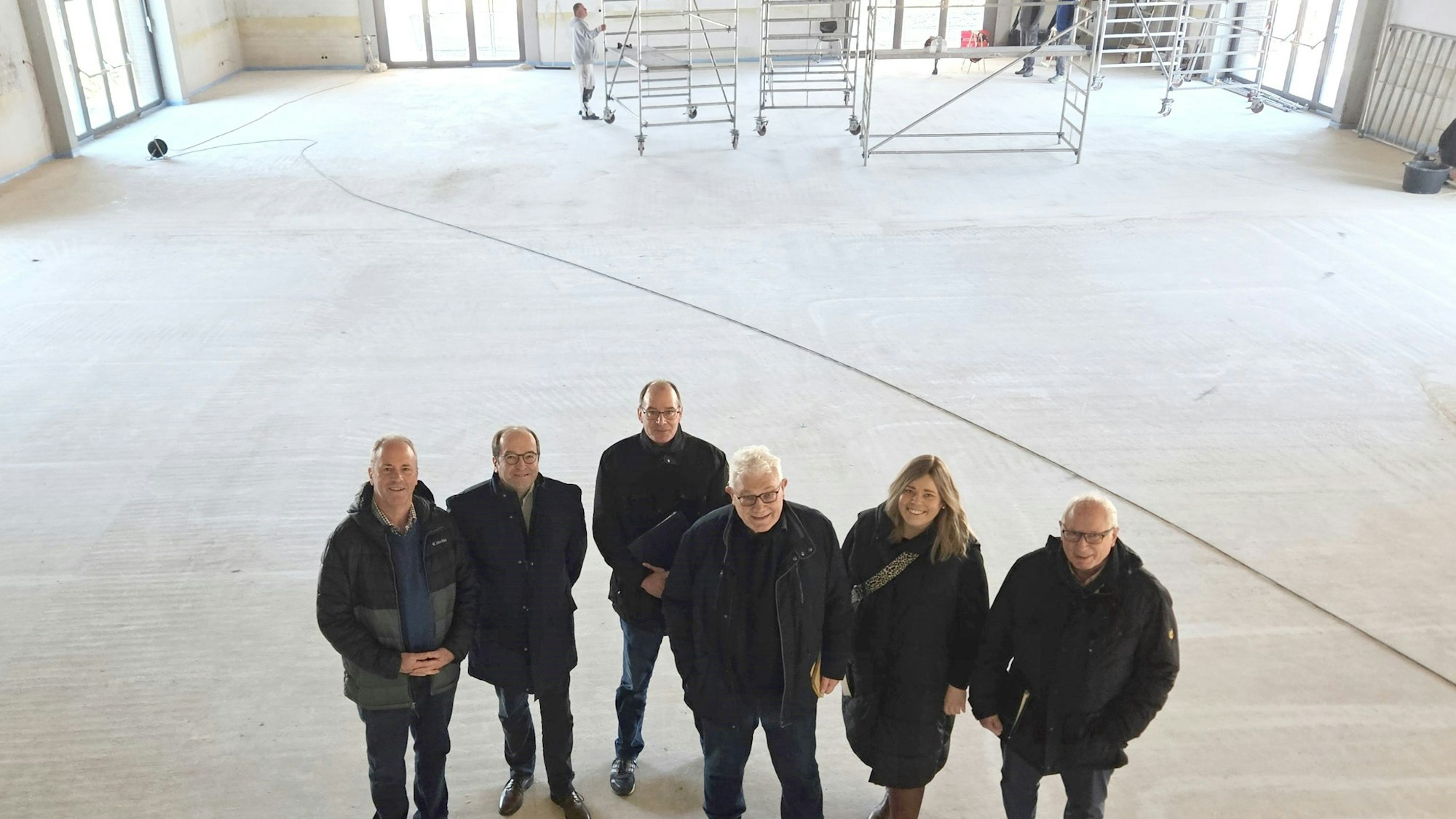 Hermann-Josef Esser, Stefan Kupp, Lothar Schatten, Gottfried Schnitzler, Nadine Schwendtner und Alois Poth vom Bürgerverein stehen in der leeren Halle, im Hintergrund sind Gerüstwagen zu sehen.