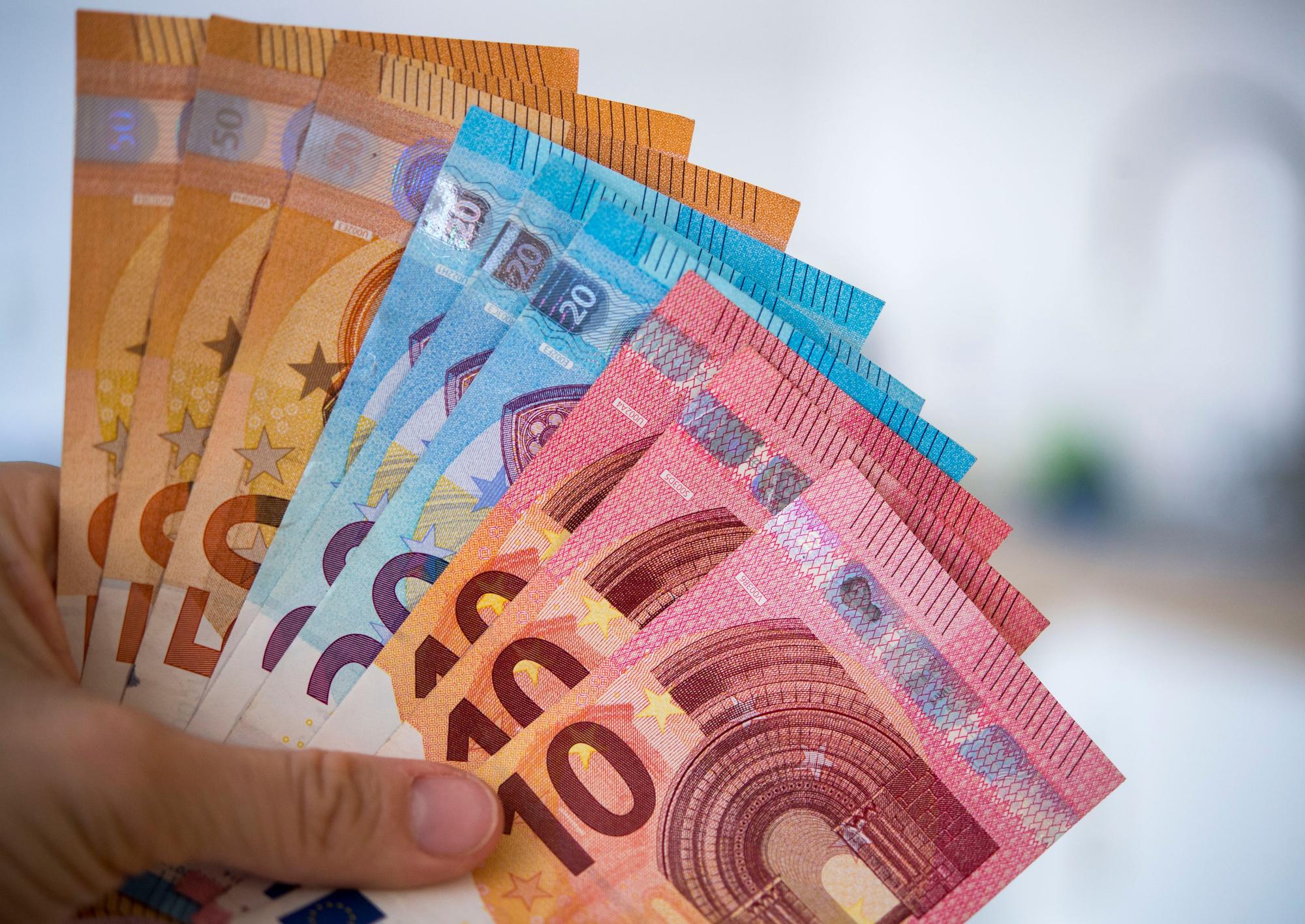 Eine Person hält Banknoten gefächert in der Hand.