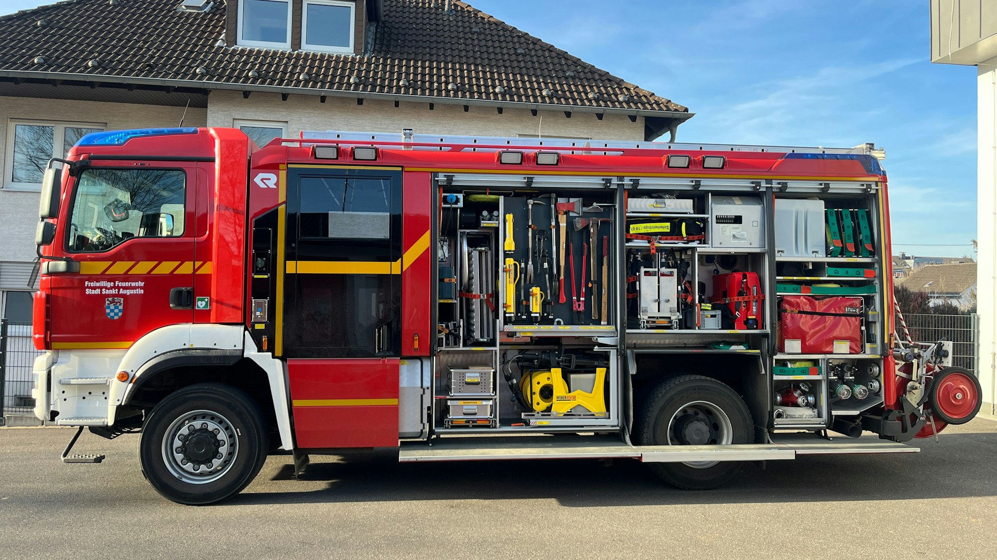 Ein Feuerwehrfahrzeug steht vor einem Gerätehaus.
